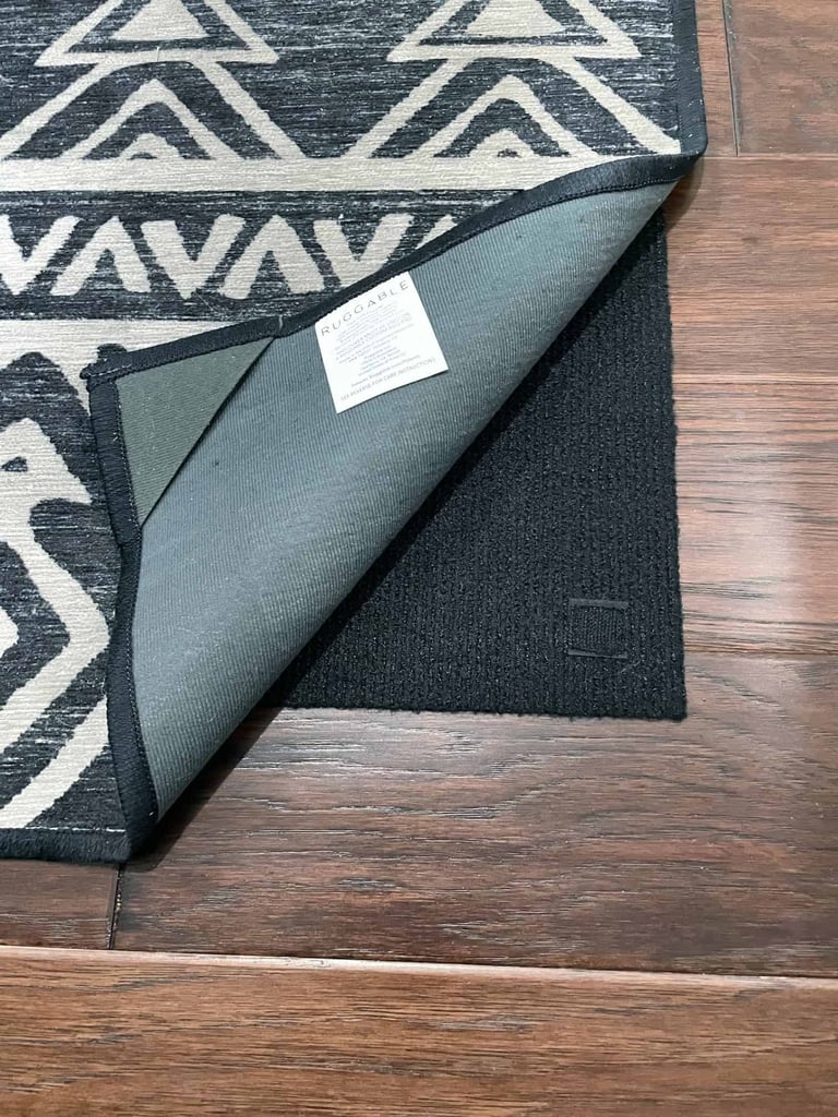 a black and white rug on a wood floor