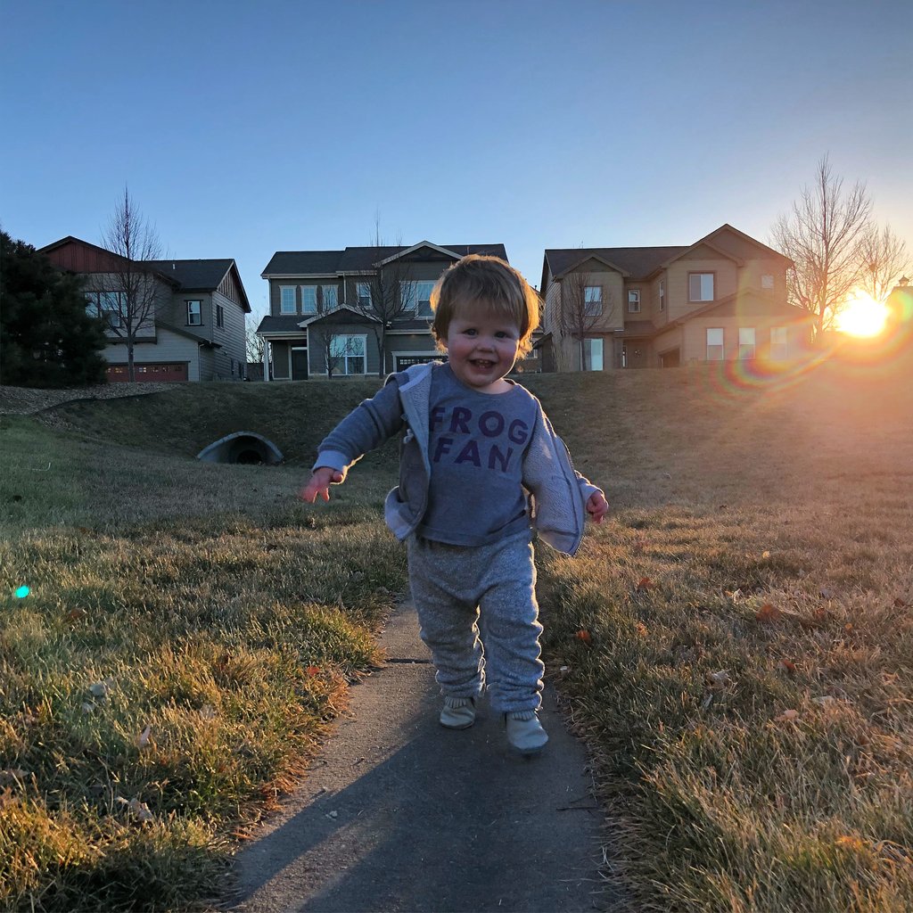 a child walking on a path in a grassy area with houses in the background