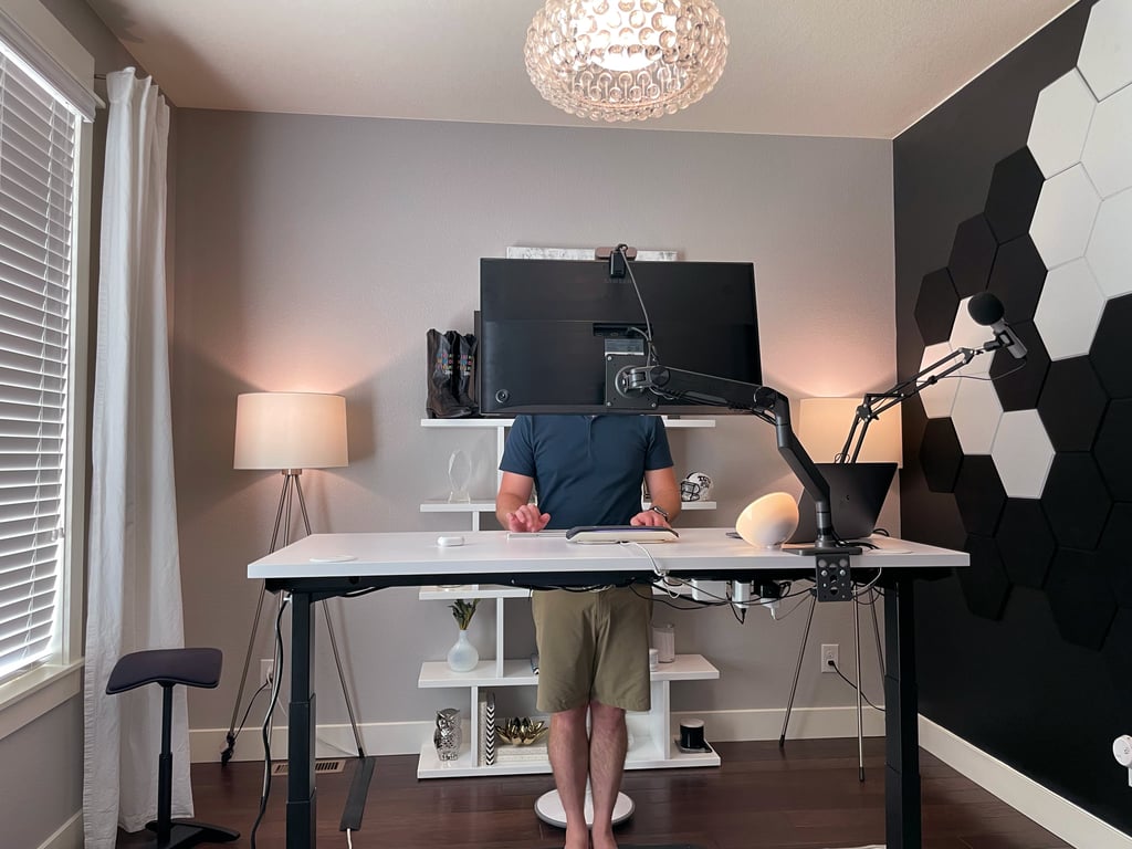 a man standing at a desk with a computer screen over his head