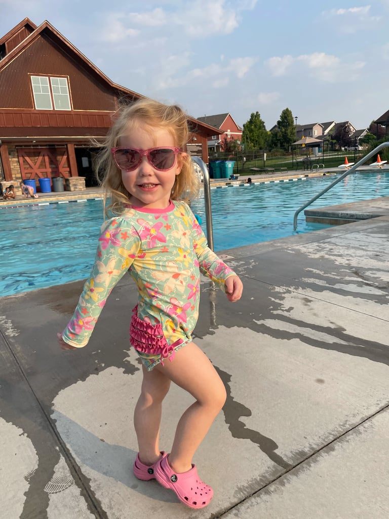 a girl in sunglasses standing in front of a pool