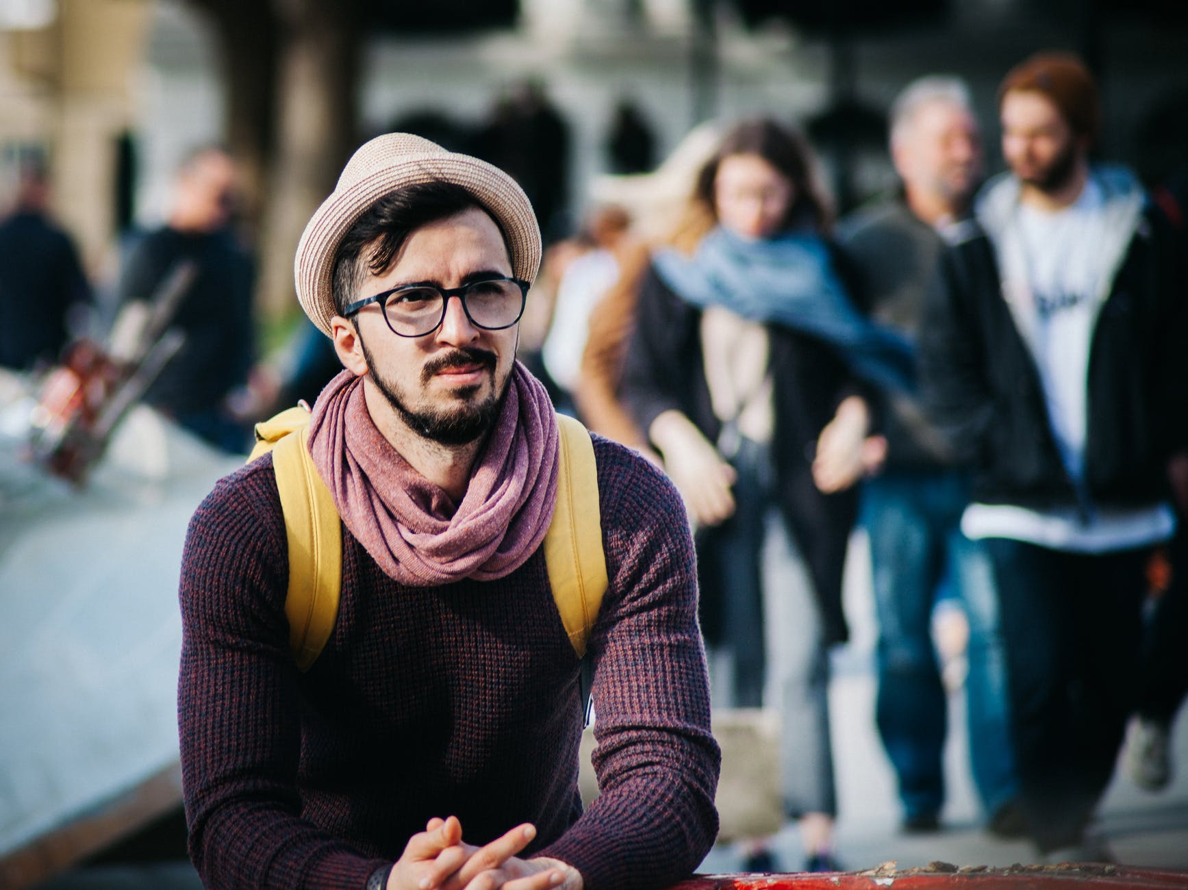 man sitting next to couple of person walking on the street during daytime