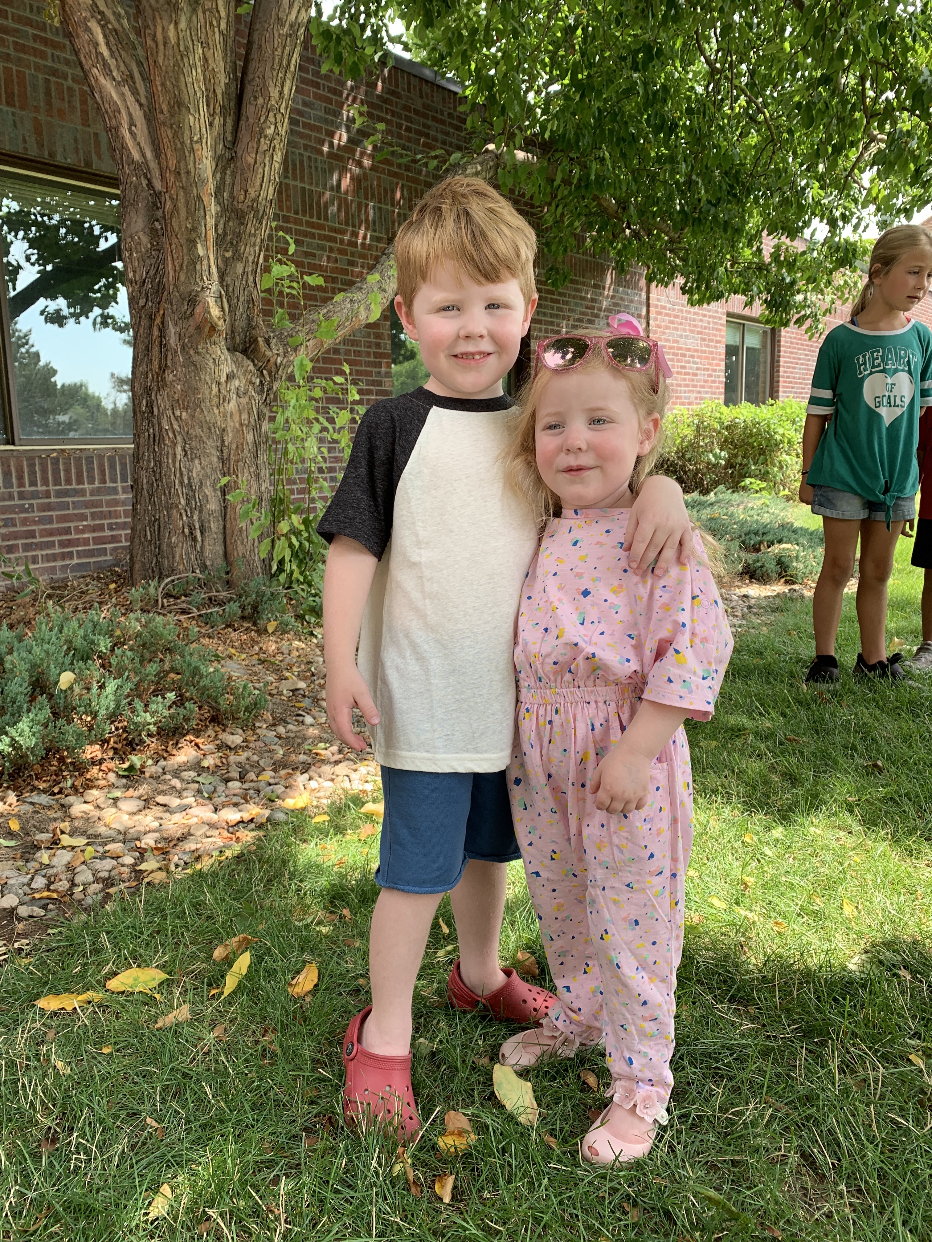 a boy and girl standing in grass